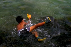 Boy catches yellow tang fish Puuhonua o Honaunau