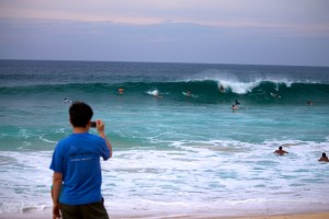 boy photographs surfers at Pipeline